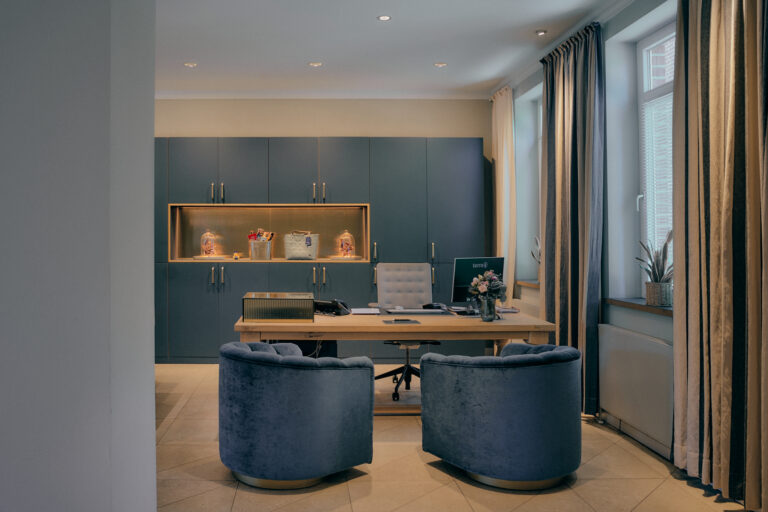 Modernes Büro mit blauen Samtstühlen, Holzschreibtisch, Pflanzen, Sonnenlicht.