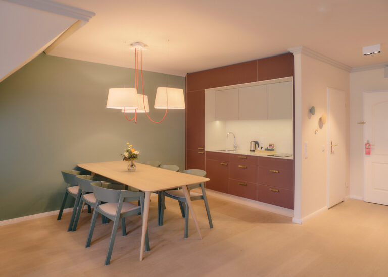 Modernes Esszimmer mit grünen Stühlen, kastanienbraunen Schränken und frischem Dekor.