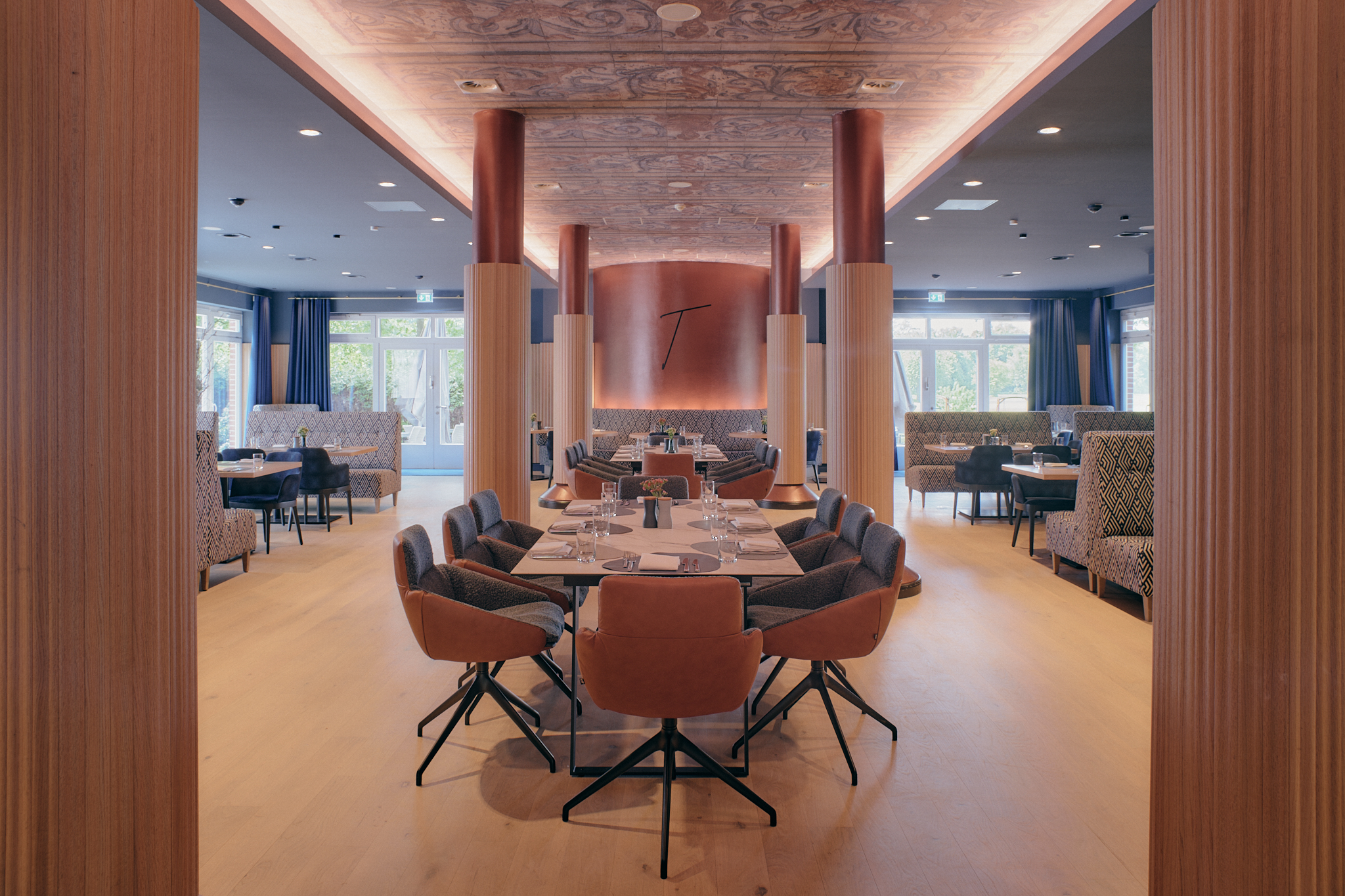 Helles Hotelrestaurant mit Holzböden, Kabinen und orangefarbenen Akzenten.