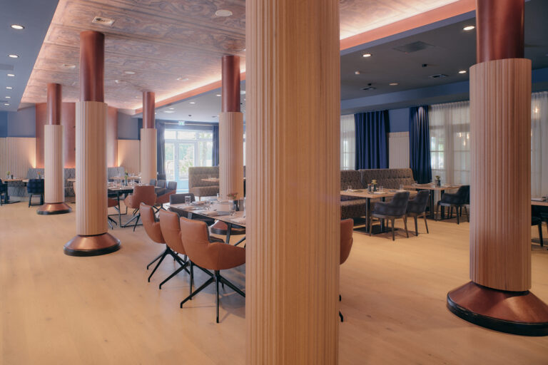 Modernes Hotelrestaurant mit Holzböden, Lederstühlen und großen Fenstern.