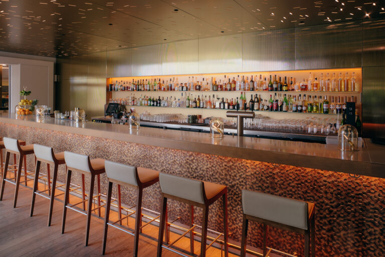 Moderne Hotelbar in Hamburg mit Metalltheke, warme Beleuchtung.