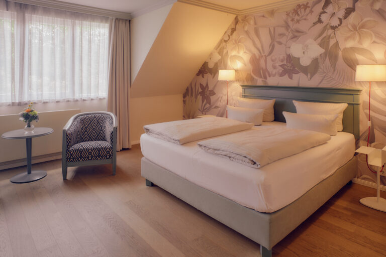 Gepflegtes Doppelbett, Blumentapete, Holzboden, sanfte Beleuchtung.