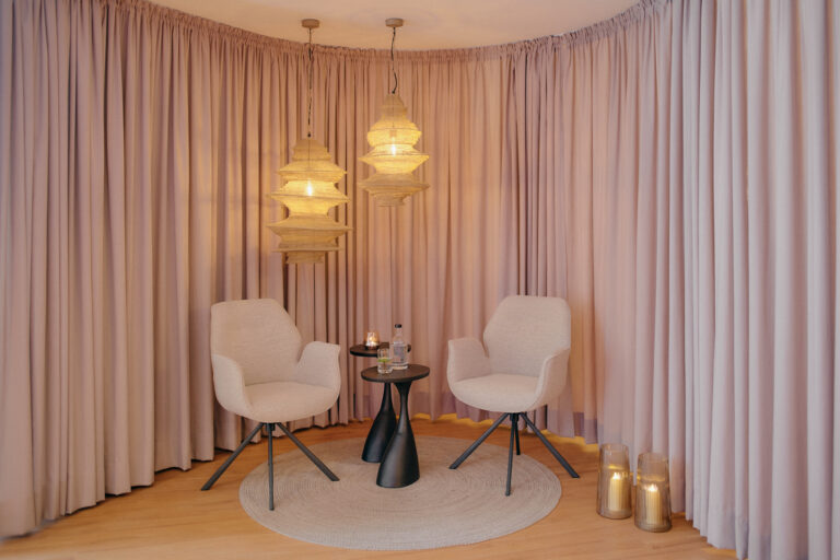 Beigefarbene Stühle, ein schwarzer Tisch und sanftes Licht sorgen für ein ruhiges Spa-Ambiente.