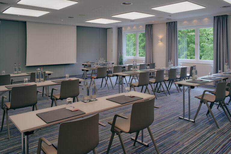 Moderner Hamburger Konferenzraum mit Tischen, Projektionsfläche, Tageslicht.