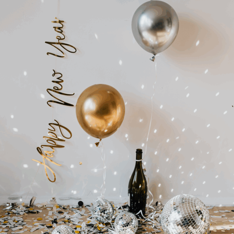 Nyebrunch_decoration_gold_silver_balloons, disco balls and confetti light up under the "Happy New Year" wall sign.