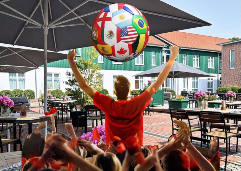Hotel-mit-Hund-in-Hamburg zeigt eine Person in rotem Hemd, die mit der Menge einen mit Nationalflaggen bedeckten Fußball feiert.